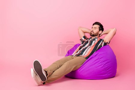 Ganzkörperfoto von Mittagsschlaf Mann entspannen schlafend unbeschwert auf bequemen Sitzsack Lounge Room isoliert über rosa Farbhintergrund.