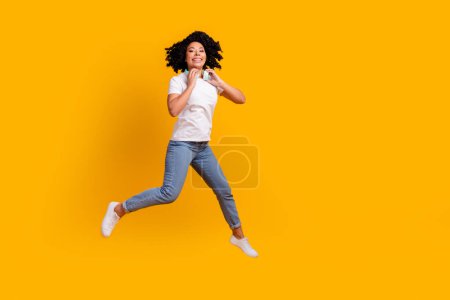 Full length photo of funky pretty lady dressed white t-shirt jumping enjoying music headphones empty space isolated yellow color background.