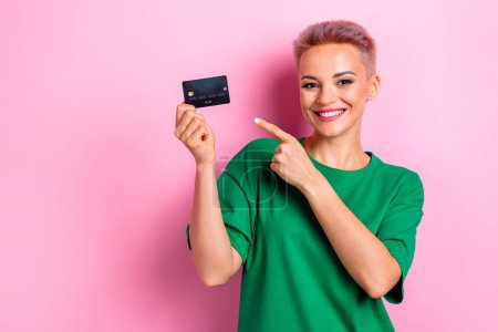 Photo of charming woman wear stylish clothes hold bank card recommend nfc cashless payment empty space isolated on pink color background.