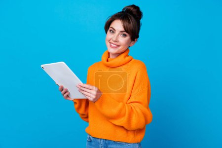 Photo of cheerful positive woman dressed orange sweater chatting apple samsung modern device isolated blue color background.