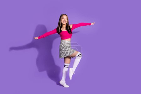 Full body photo of good mood korean schoolgirl wear crop top plaid skirt long socks holding palms like wings isolated on violet background.