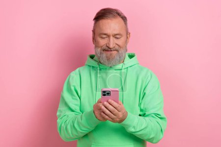 Photo of good mood funky man wear green sweatshirt reading news modern gadget isolated pink color background.