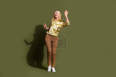 Ganzkörperfoto mit Spaß positive Rentnerin tanzen gekleidet casual Kleidung isoliert auf khaki Farbhintergrund.