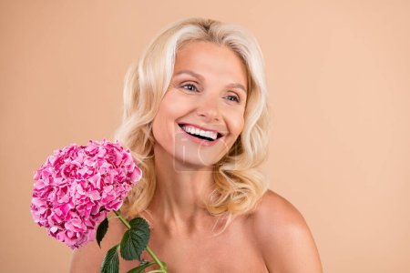 Photo of charming senior lady hold hydrangea flower enjoying pampering skincare bodycare for soft skin isolated pastel color background.