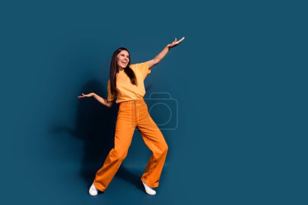 Ganzkörperlänge Foto von cool tanzen junge positive Frau hob die Handflächen nach oben machen Wellen bewegt sich isoliert über dunkelblauen Farbhintergrund.