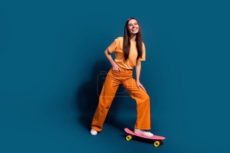 Pleine taille photo de la taille du corps heureux sourire brune chevelure dame ride longboard profiter de son passe-temps faire des tours isolés sur fond de couleur bleu foncé.