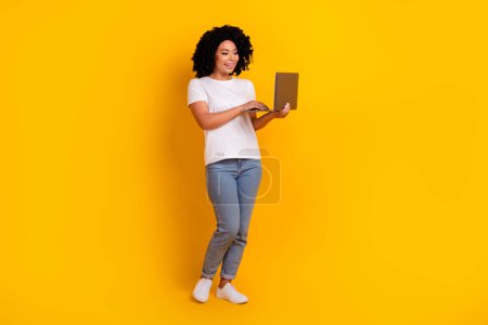 Full length photo of sweet charming woman wear white t-shirt reading emails modern device isolated yellow color background.