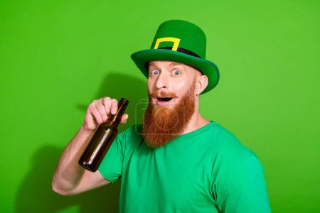 Photo of impressed funky person hand hold drink glass beer bottle isolated on green color background.