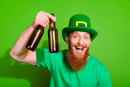 Portrait of overjoyed nice person hand hold glass beer bottles chill isolated on green color background.