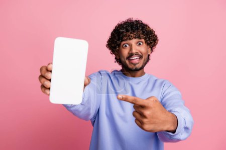 Photo portrait of nice young guy point excited white screen device dressed stylish blue outfit isolated on pink color background.