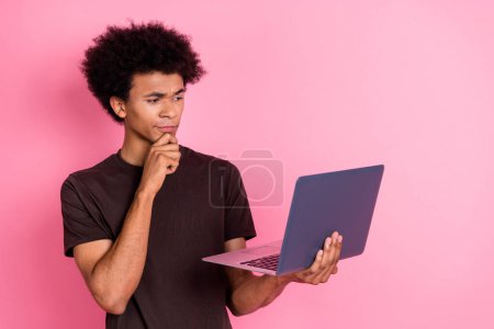 Photo of young thoughtful pensive guy touch chin doing homework for university lecture difficult tasks isolated on pink color background.