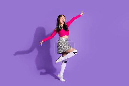 Full size photo of lovely girl dressed checkered skirt stand on one leg look at black friday empty space isolated on purple background.