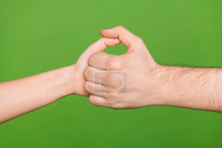 Foto de dos personas manos palmas que se divierten jugando juego de guerra pulgar aislado color verde fondo.