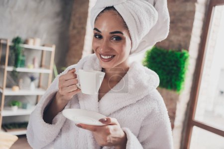 Portrait photo de jolie jeune fille buvant du thé délicieux relax tête enveloppée serviette habillée peignoir beauté routine concept maison.