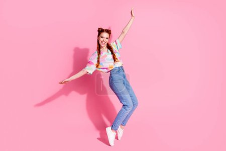 Full size photo of carefree eccentric funny girl dressed colorful blouse jeans standing on tiptoes isolated on pink color background.