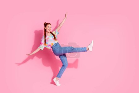 Full size photo of nice girl dressed colorful blouse jeans stand on one leg look at discount empty space isolated on pink color background.