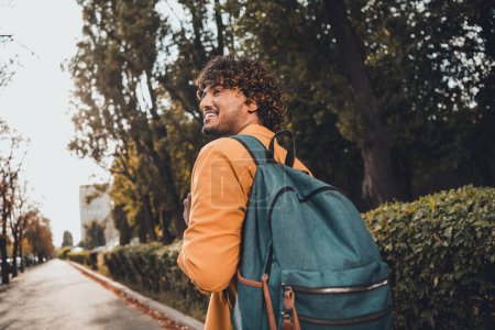 Photo of positive nice young hispanic man with backpack exploring city streets vacation trip travel pastime promenade outside.