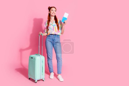 Full size photo of dreamy girl dressed colorful blouse hold suitcase passport look at promo empty space isolated on pink color background.
