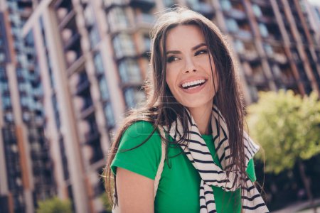 Photo of sweet dreamy young laughing lady dressed green outfit smiling walking street outdoors sunny spring day in city on background.