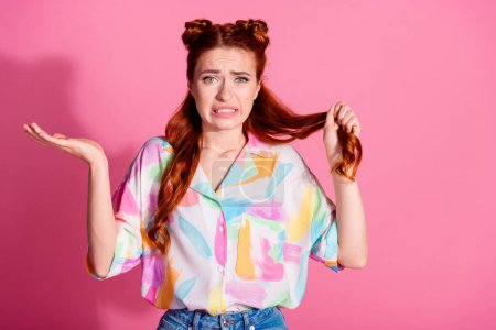 Retrato de mujer confundida despistada usar camisa de impresión mantenga el pelo foxy pensar para cortar los hombros encogimiento de hombros rizos aislados en el fondo de color rosa.