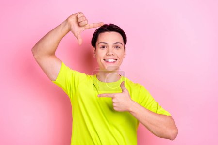Photo portrait of handsome teen male fingers show photo frame cadre wear trendy yellow garment isolated on pink color background.