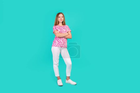 Foto de tamaño completo de bastante adolescente cruzó las manos confiado pose desgaste moda impresión rosa traje aislado en el fondo de color cian.