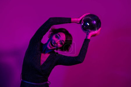 Photo portrait of lovely young lady hold excited disco ball wear trendy overall garment isolated on neon light pink color background.