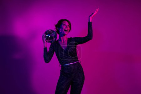 Photo portrait of attractive young woman hold disco ball sing wear trendy overall clothes isolated on neon light pink color background.