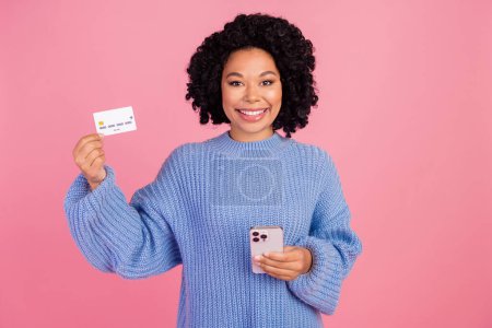 Photo portrait of pretty young girl hold device credit card dressed stylish clue knitted outfit isolated on pink color background.