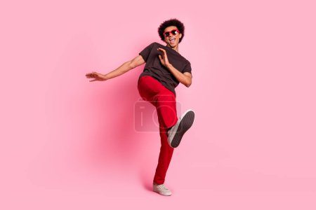Foto de cuerpo entero de macho fresco chico despreocupado en ropa de moda chill out baile relajante positivo aislado sobre fondo de color rosa.