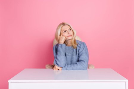 Photo of upset unsure woman wear pullover sitting office looking empty space isolated pink color background.