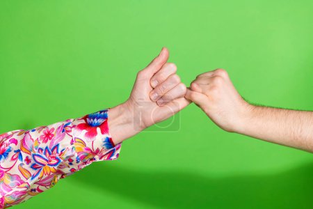 Photo de deux bras masculins féminins doigts croisés réconcilier pardonner l'autre isolé fond de couleur verte.