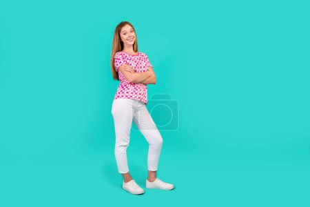Foto de cuerpo completo de la mujer adolescente agradable doblado manos confiadas pose desgaste moda impresión rosa ropa aislada sobre fondo de color cian.