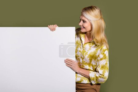 Foto der fröhlichen Frau blondes Haar Unternehmer hält Plakatwand leer Leerraum Platz für Marke isoliert auf khakifarbenem Hintergrund.