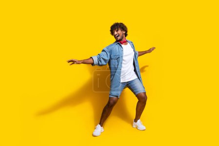 Full size photo of nice young male surfing have fun wear trendy denim outfit red scarf isolated on yellow color background.