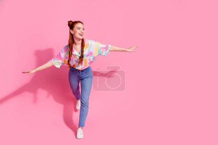 Full size photo of gorgeous girl dressed colorful blouse jeans palms like plane look at sale empty space isolated on pink color background.