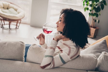 Portrait photo de jolie jeune femme assise canapé boire du vin habillé vêtements décontractés lumière du jour confortable maison salon intérieur.