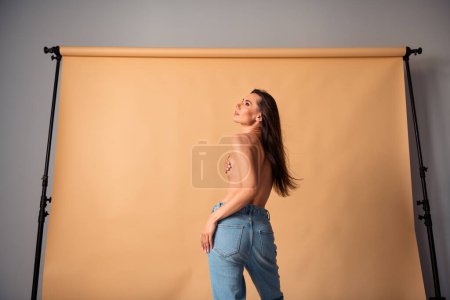 Photo non retouchée de jolie femme couvrir main poitrine regarder posant pour photographe en studio isolé fond de couleur pastel.