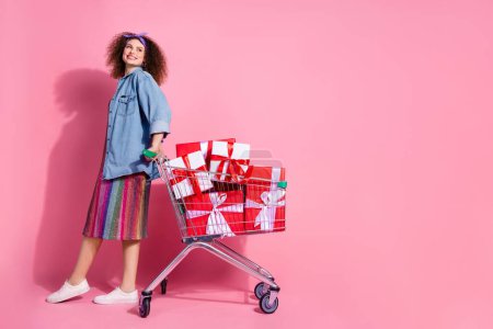 Full length photo of funky dreamy lady dressed jeans outfit buying gifts looking empty space isolated pink color background.