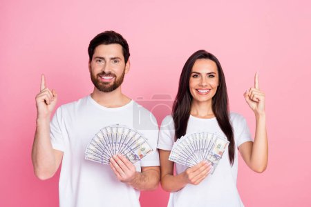 Photo portrait of nice young couple hold money fan point empty space wear tenue blanche tendance isolé sur fond de couleur rose.