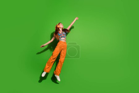 Foto in voller Größe von hübschen jungen Frau springen Hand halten leeren Raum tragen Top isoliert auf hellgrünem Hintergrund.