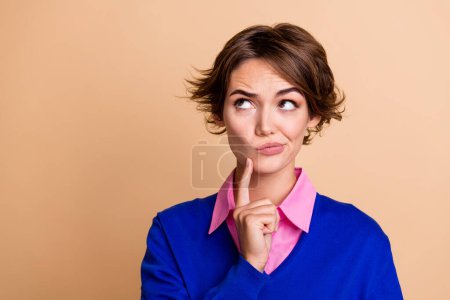 Photo portrait of pretty young girl look skeptical unsure empty space dressed stylish blue outfit isolated on beige color background.