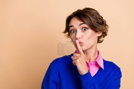 Photo portrait of pretty young girl finger touch lips shh keep secret dressed stylish blue outfit isolated on beige color background.