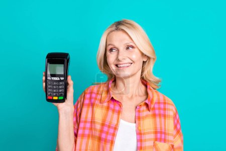 Photo of smart positive person with straight hair dressed checkered shirt look at payment terminal isolated on teal color background.