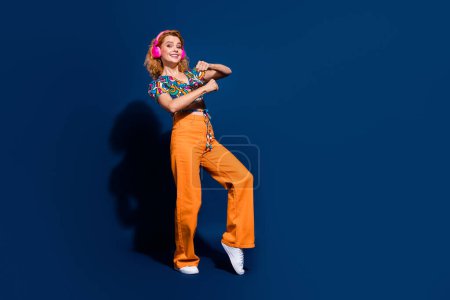Full size photo of pretty young woman dance empty space wear top isolated on dark blue color background.