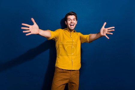 Photo portrait of nice young male stretch hands want hugging wear trendy yellow garment isolated on dark blue color background.