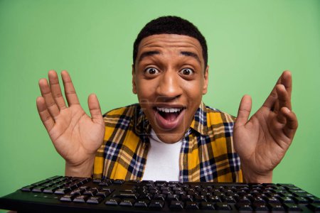 Photo of funky impressed guy raise arms open mouth unexpected reaction computer keyboard isolated on green color background.