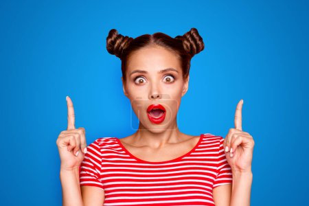 Close up portrait of astonished girl with wide open mouth gesturing index fingers up isolated on red background. Advertisement concept.