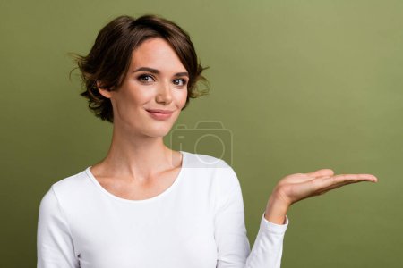Photo portrait of attractive young woman palm hold empty space sales wear trendy white clothes isolated on khaki color background.