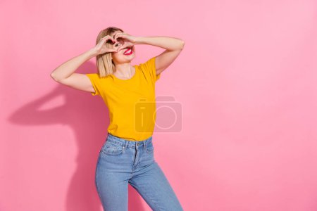 Foto von ziemlich süße Dame gekleidet gelbes T-Shirt zeigt Arme Herz bedecken Auge leeren Raum isoliert rosa Farbe Hintergrund.
